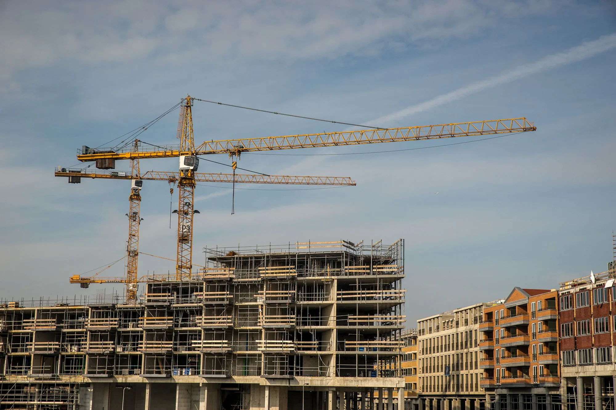 Obra residencial en construcción con grúas bajo un cielo despejado